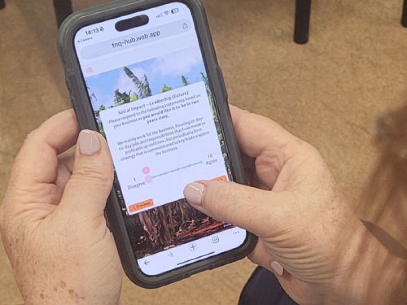 Hands holding a smartphone using the AgValuate web app with a slider question to assess farm innovation readiness.