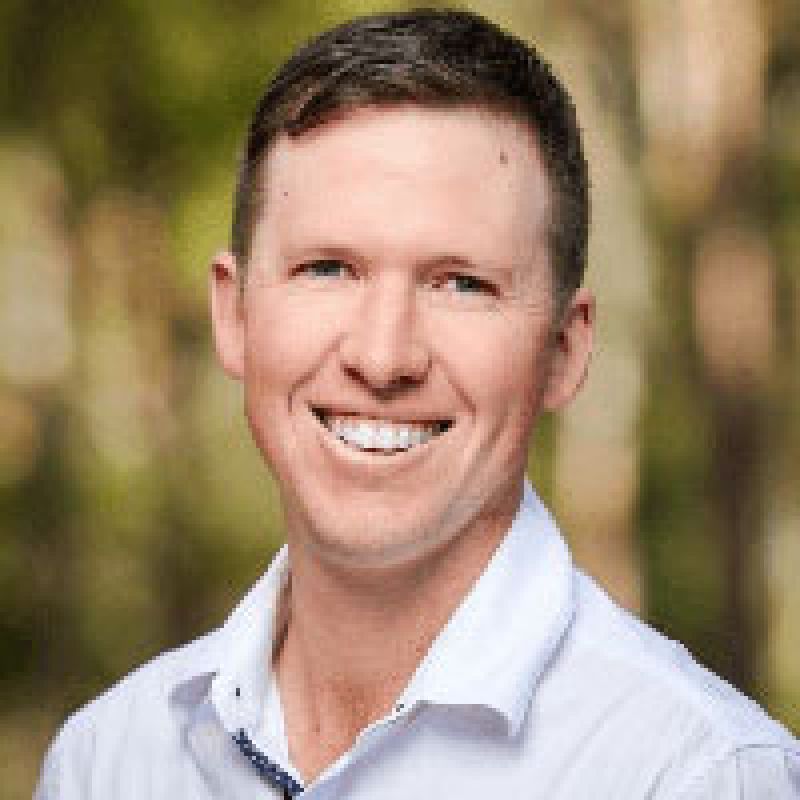 Younger man in white shirt smiling at camera