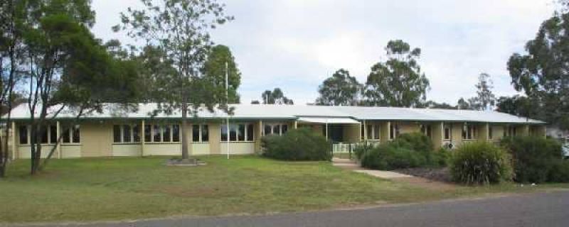 Long, single-storey building at the J Bjelke-Petersen Research Facility with a lawn, footpath and surrounding trees.