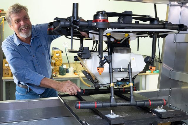 A man in a workshop inspecting a large agricultural drone, highlighting its use in coastal farming systems