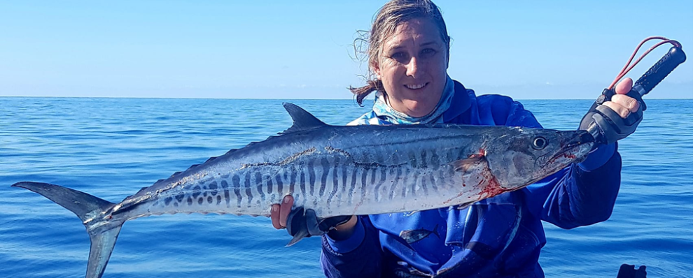 Lady holding large fish in front of the ocean