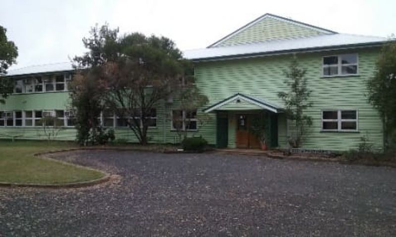 Two-storey green building at the Brian Pastures Research Facility with a central entry and driveway in front.