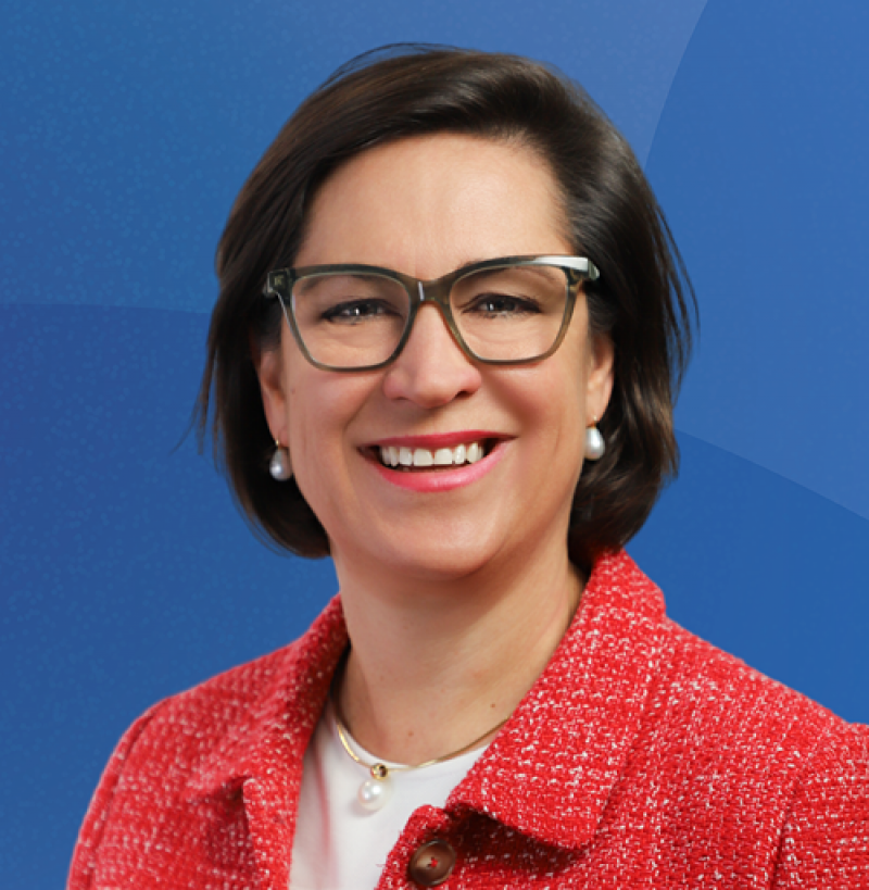 Lady with glasses and dark bobbed hair smiles at camera
