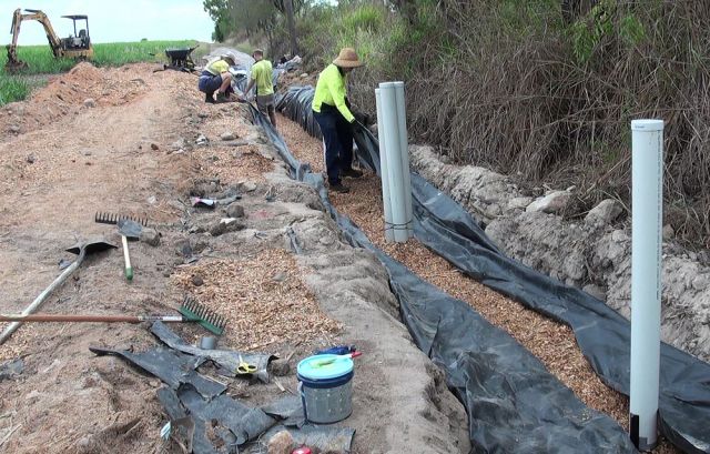 Farmers constructing a bioreactor system near a farm drainage area to improve water quality