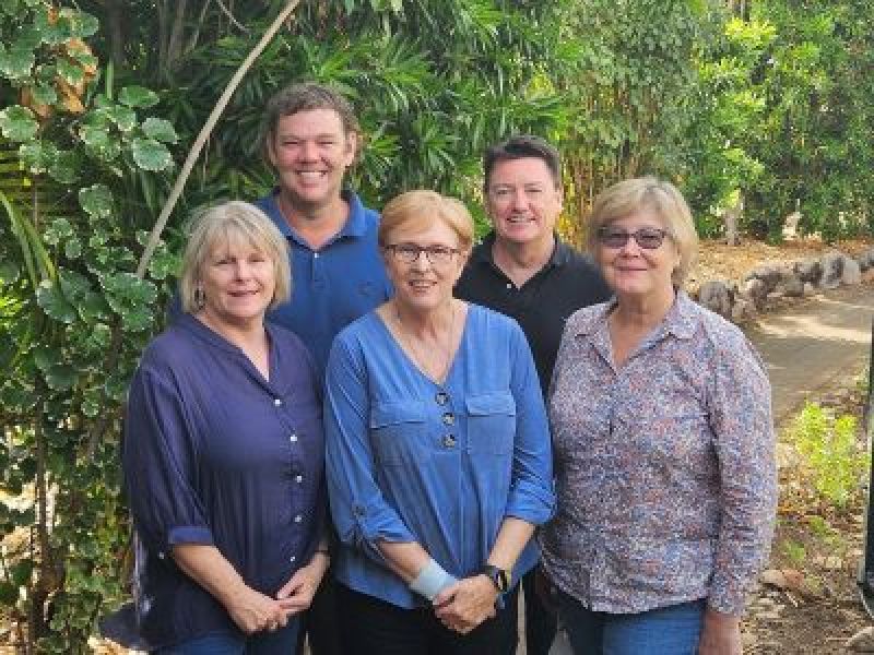 Five team members standing together in a garden, representing Queensland’s engagement and capacity-building initiatives