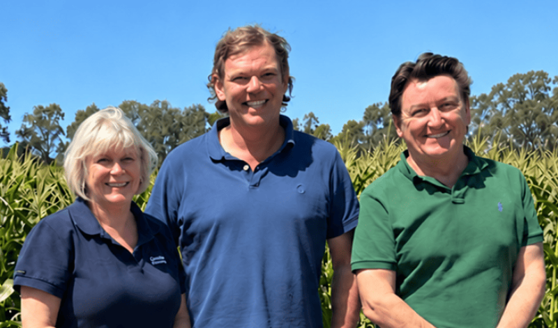 1 lady and 2 men stand together in front of a green crop