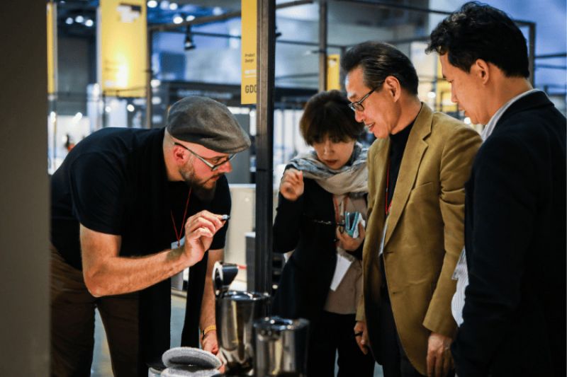 Neil Davidson shows a small item to a group of three people.