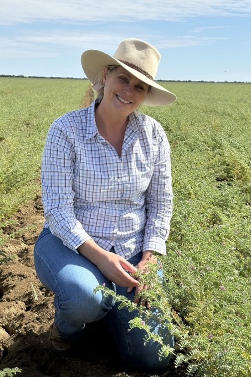A female kneeling in a field looking at the camera