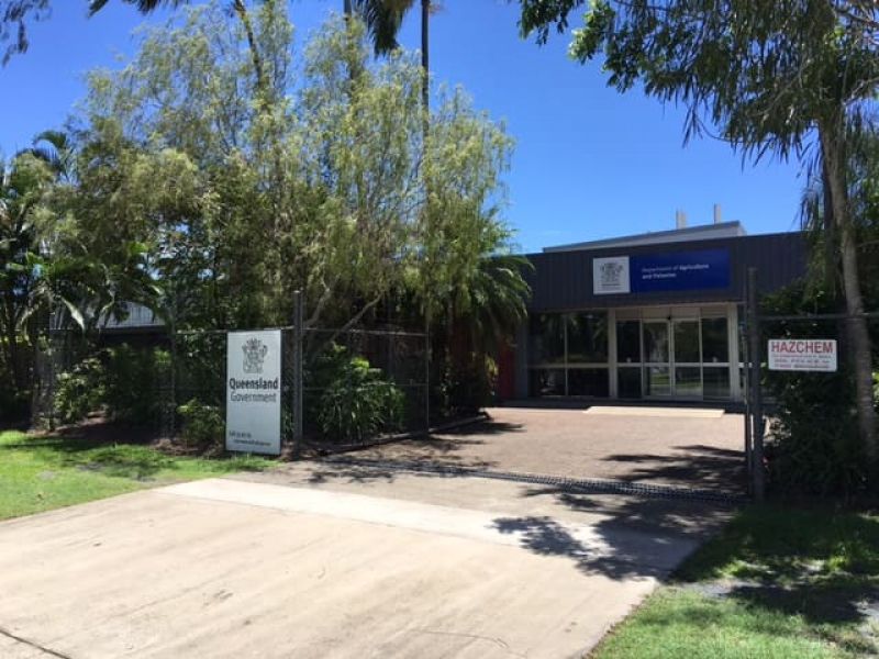 Gated driveway and entrance to the Redden Street Research Facility, with Queensland Government signage and tropical landscaping.
