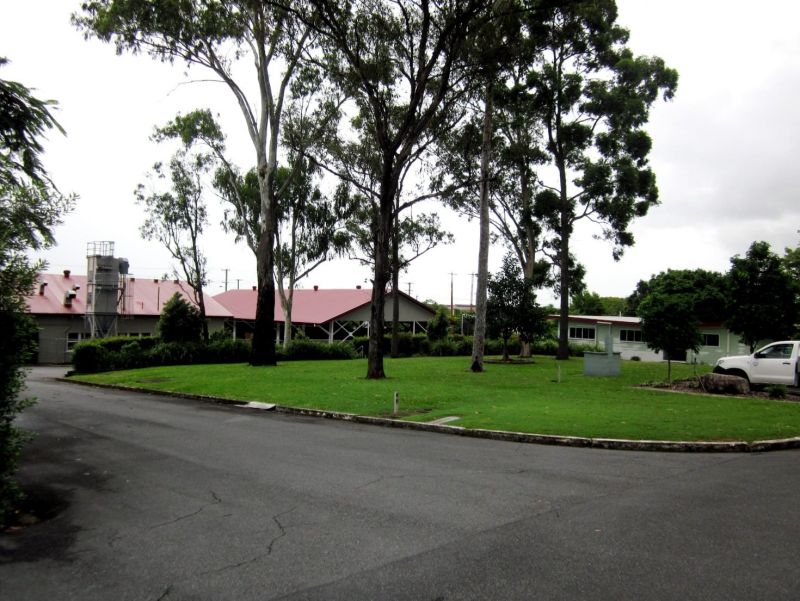 Wide view across the Salisbury Research Facility grounds with large trees, lawns and several buildings with red roofs.
