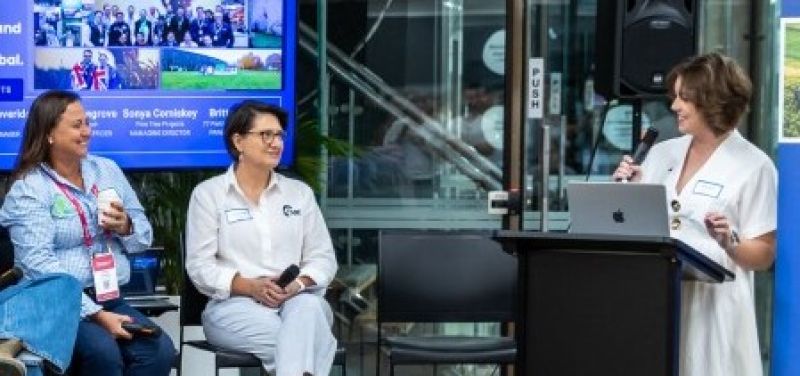 2 women on chairs with a microphone and a woman standing behind a lectern