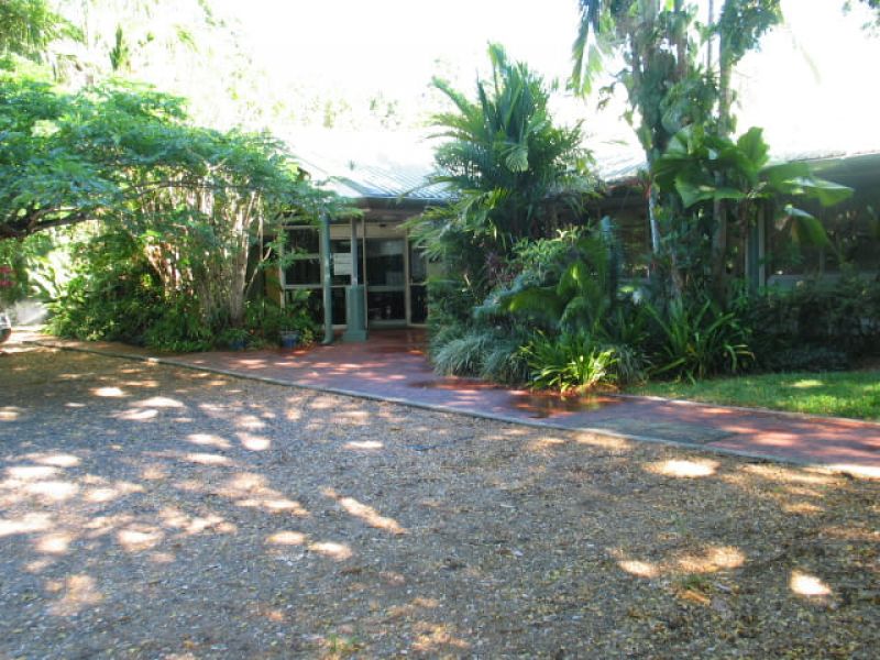 Shaded entrance area at the South Johnstone Research Facility with a path leading to glass doors and dense tropical plants.