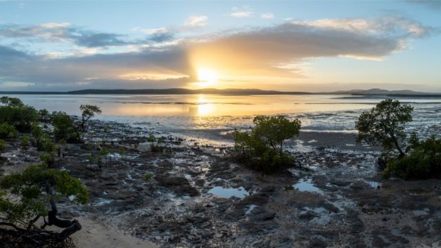 A sunrise peeks through clouds off Queensland’s east coast