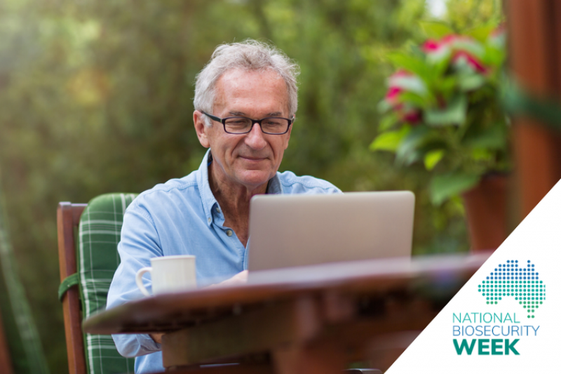 Person sitting outdoors at a table using a laptop and a National Biosecurity Week logo in the corner.