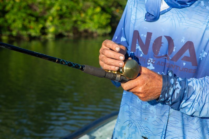 A fishing rod and reel in the hands of a man in a blue shirt